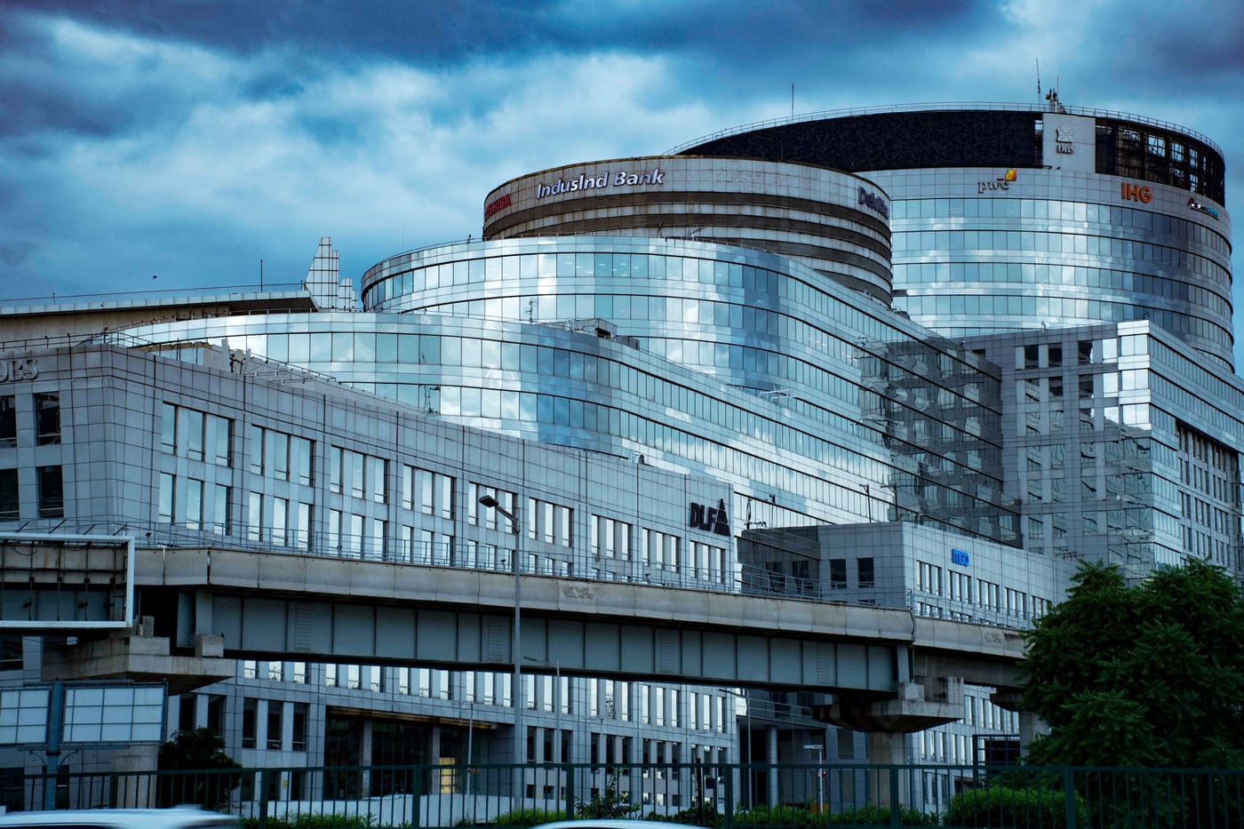 A modern glass bank building under a stormy sky