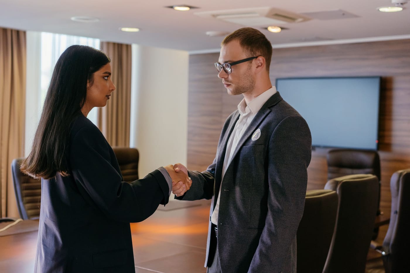Two professionals shaking hands in a conference room after an interview