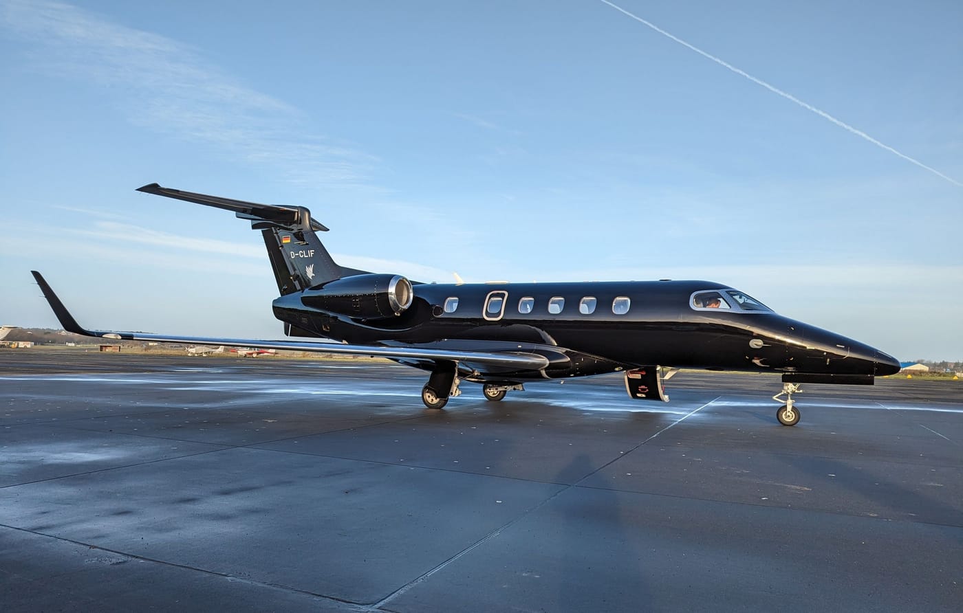 A black private jet parked on a sunny airport apron