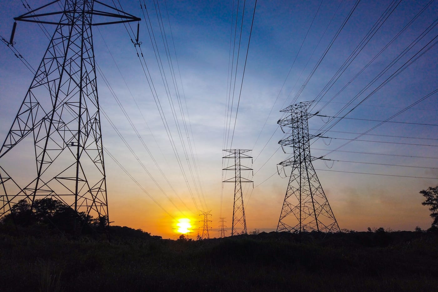 Electricity transmission towers silhouetted at sunset