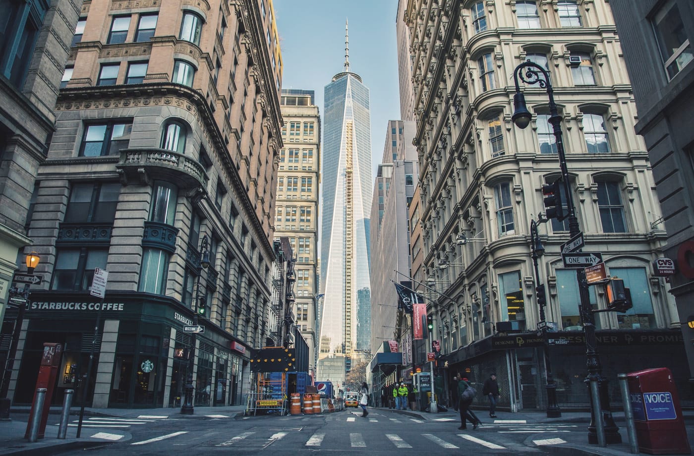 A city street lined with historic buildings leading to a modern skyscraper